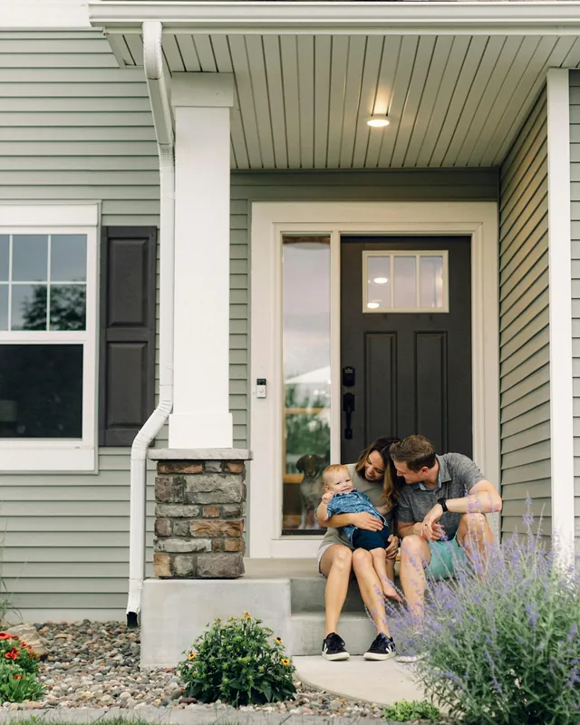 Happy family sitting on the front steps of their home