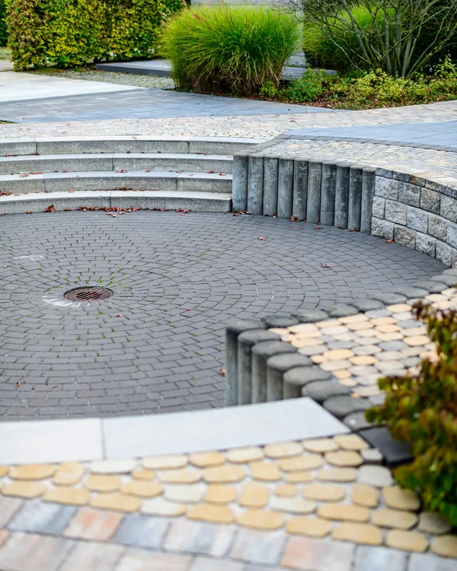 Curved paver patio with stone steps and seating wall