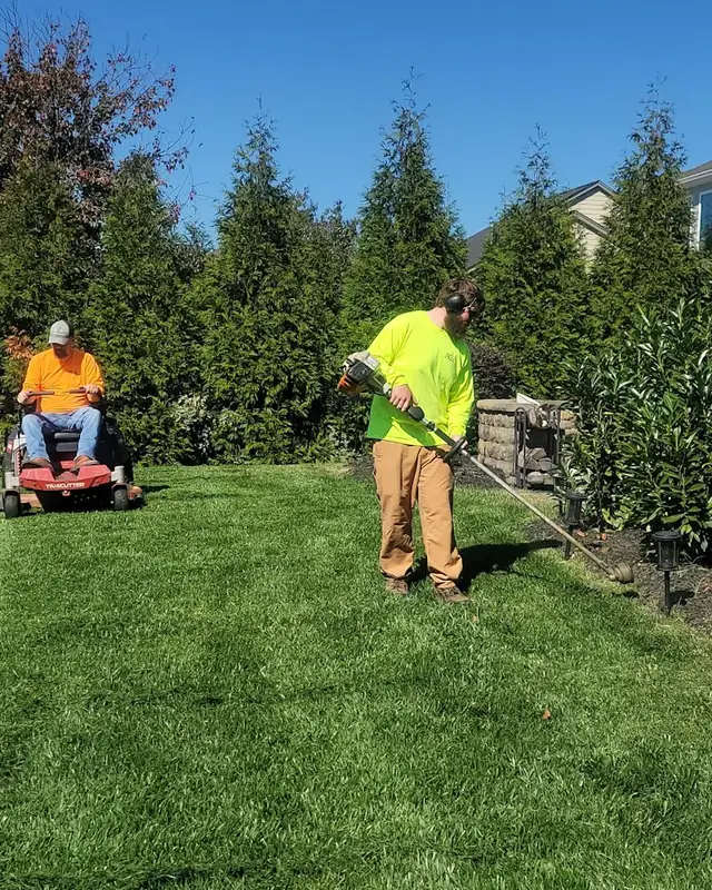 Landscaping crew mowing and edging a freshly striped lawn